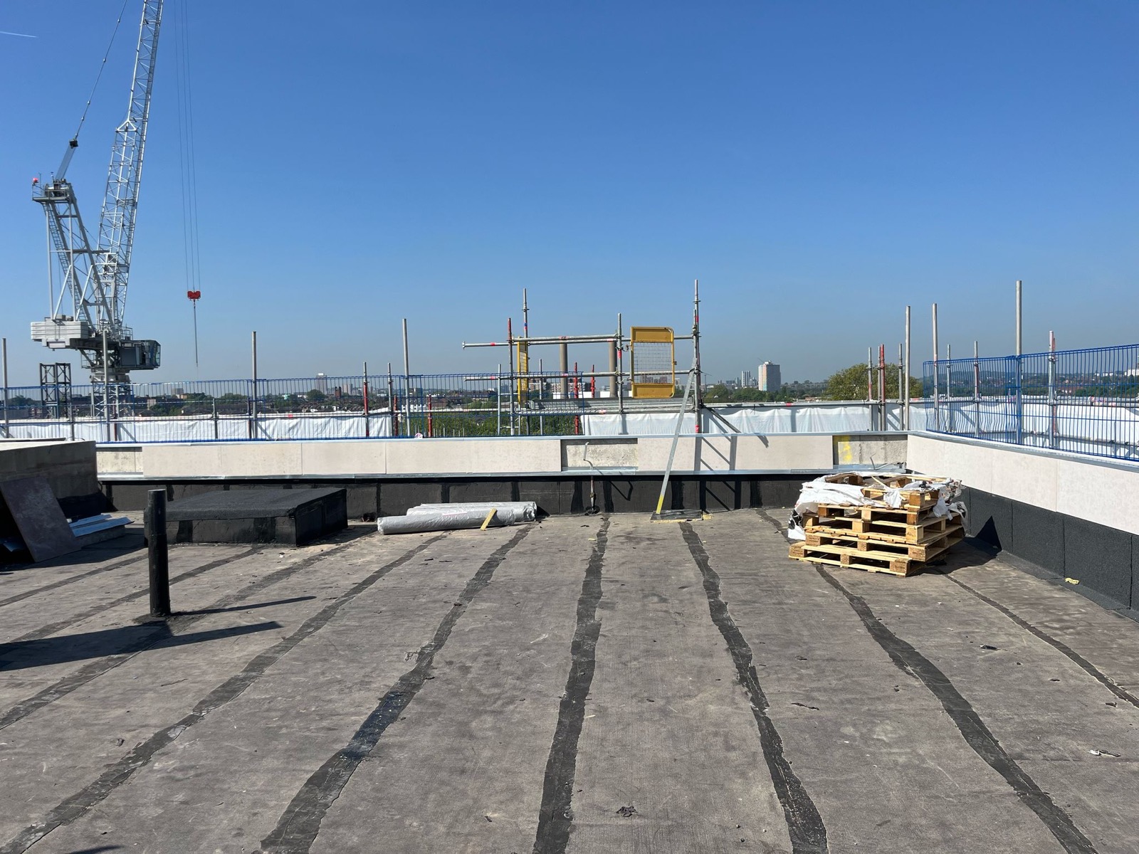 Flat roof waterproofing work photographed on a construction site.